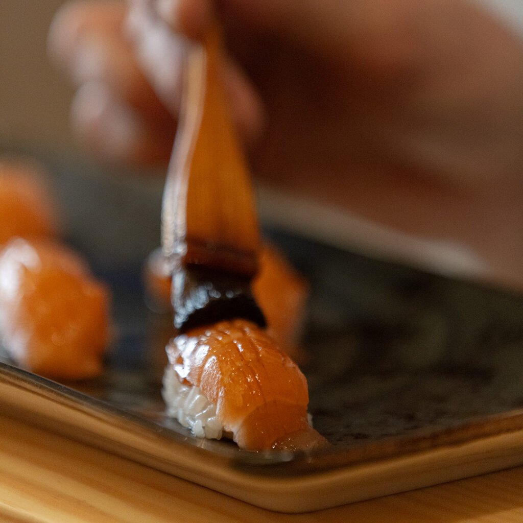 El chef pincela con nikiri un nigiri de salmón